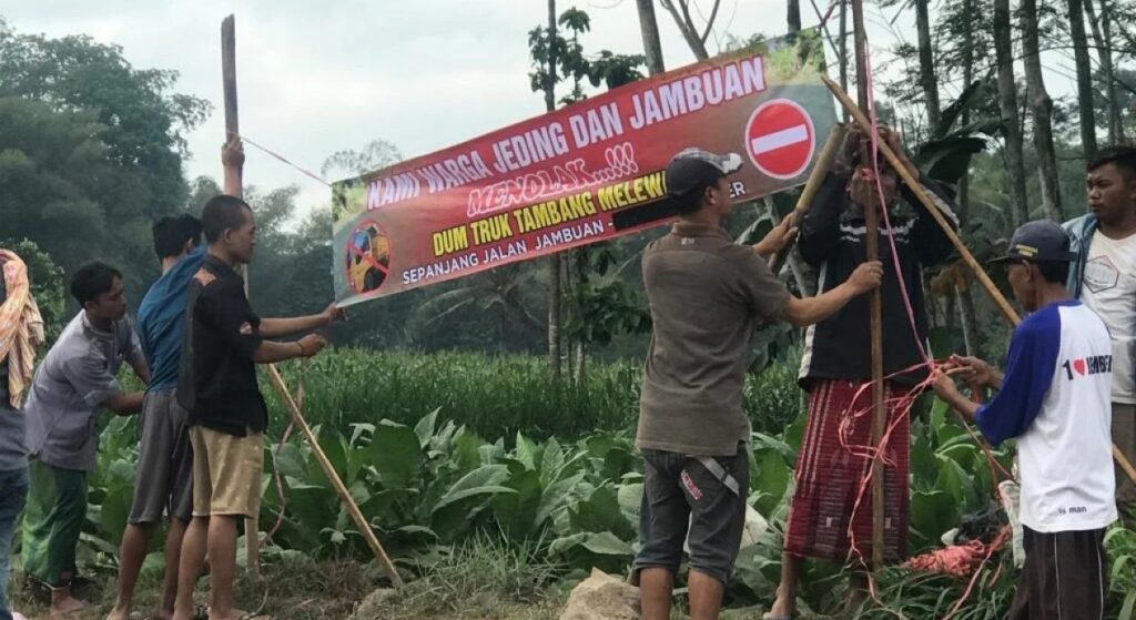 Warga pasang banner penolakan dum truk dari tambang illegal melewati jalan desa. Sumber foto: Istimewa.