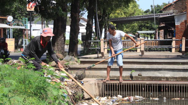 Ilustrasi warga saat membersihkan saluran drainase. Sumber foto: iStock.