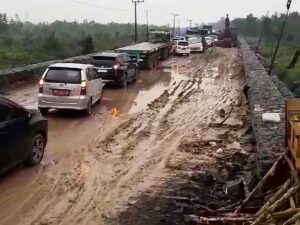 Kendaraan berusaha melewati satu titik ruas jalan yang rusak.