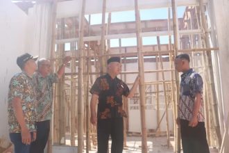 Kades Gumulan Busroni (tengah) bersama perangkat desa meninjau progres pembangunan ruangan baru untuk kantor desa Gumulan. Foto : Achmad RW/Radar Jombang