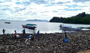 keterangan foto: warga memungut sampah di pantai, sumber foto: Antara