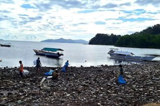 keterangan foto: warga memungut sampah di pantai, sumber foto: Antara