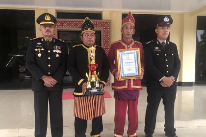 Kasat Binmas Polres Bombana, AKP Abdul Kadir (ujung kiri), Kepala Desa Marga Jaya, Suharto (kedua dari kiri) dan Bhabinkamtibmas Polsek Lantai Jaya, Bripka Yusri (ujung kanan) saat menerima piala lomba Pos Kamling. Sumber Foto: Istimewa