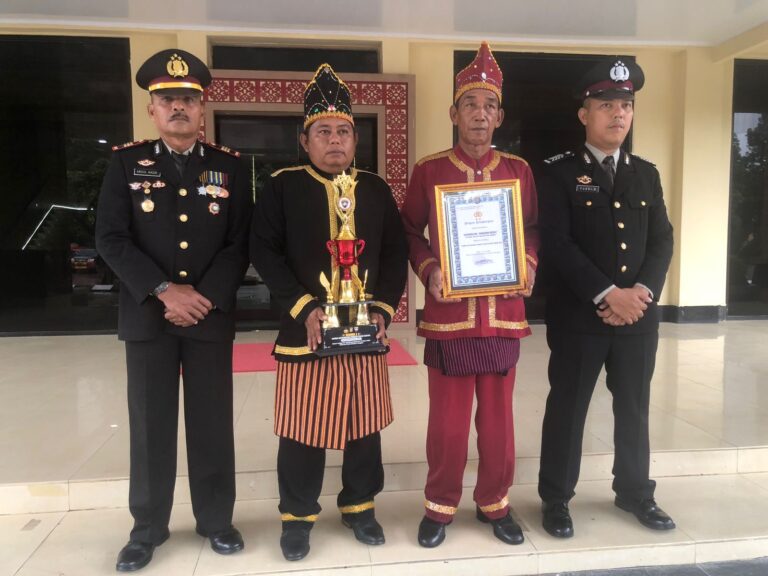 Kasat Binmas Polres Bombana, AKP Abdul Kadir (ujung kiri), Kepala Desa Marga Jaya, Suharto (kedua dari kiri) dan Bhabinkamtibmas Polsek Lantai Jaya, Bripka Yusri (ujung kanan) saat menerima piala lomba Pos Kamling. Sumber Foto: Istimewa