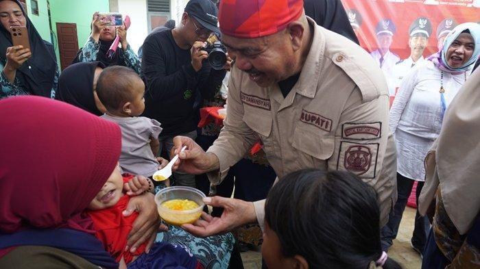 Bupati Kutai Kartanegara, Edi Damansyah saat memberikan makanan tambahan bergizi untuk balita usai meresmikan Posyandu Mawar Desa Perian.