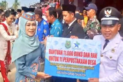 Penjabat Ketua TP PKK Kabupaten Kapuas Hj Lisdayanti, menyerahkan bantuan 11 ribu buku beserta rak secara simbolis kepada Kepala Desa Pulau Telo.