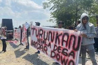 Massa membeber spanduk tuntutan saat di balai desa Banjardowo Kecamatan Kabuh. Sumber : beritajatim.com