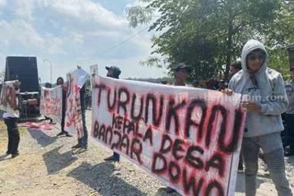 Massa membeber spanduk tuntutan saat di balai desa Banjardowo Kecamatan Kabuh. Sumber : beritajatim.com