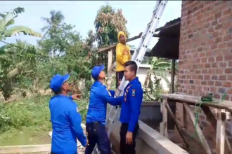 Petugas Damkarmat Lampung Selatan Membatu Warga Memperbaiki Rumah. Sumber: Lampost.co
