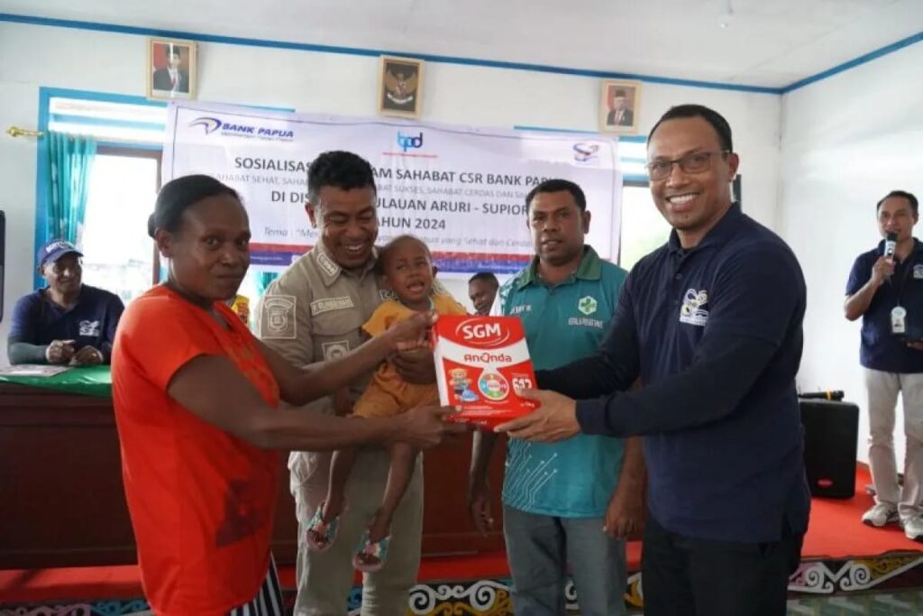 Pemimpin Divisi Sekretaris Perusahaan Bank Papua, Matheus A. Mual saat menyerahkan bantuan berupa susu bubuk kepada warga di Kampung Rayori. Sumber : Antarapapua