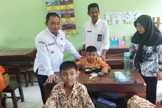 Kepala Desa Kepatihan Erwin Pribadi mendampingi Pj Bupati Jombang Teguh Narutomo saat meninjau simulasi program makan siang gratis di SDN Kepatihan. Sumber : Achmad RW/Radar Jombang