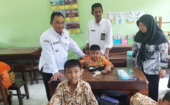 Kepala Desa Kepatihan Erwin Pribadi mendampingi Pj Bupati Jombang Teguh Narutomo saat meninjau simulasi program makan siang gratis di SDN Kepatihan. Sumber : Achmad RW/Radar Jombang