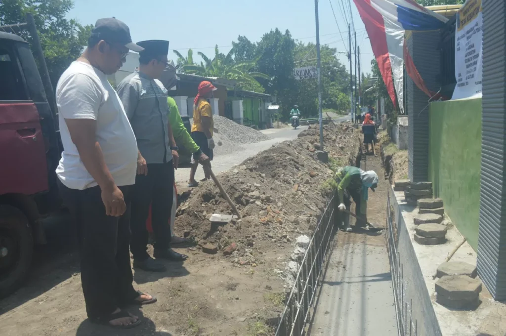 Kades Kebontemu Sirojul Munir (kaos putih) bersama perangkat desa melakukan pengecekan proyek drainase di Dusun Kabunan. Sumber : Ainul Hafidz/Radar Jombang