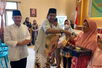 Kepala Desa Kepatihan Erwin Pribadi didampingi Camat Jombang Heri Prayitno, saat menyerahkan bantuan kompor kepada warga,. Sumber : Anggi Fridianto/Radar Jombang