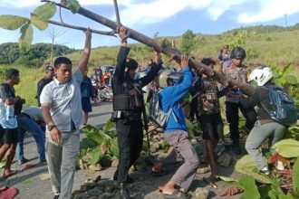 Sejumlah warga dan Personel Brimob saat membersihkan blokade jalan. Sumber : detik.com