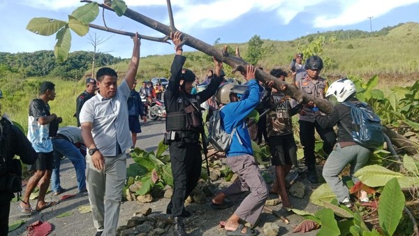 Sejumlah warga dan Personel Brimob saat membersihkan blokade jalan. Sumber : detik.com