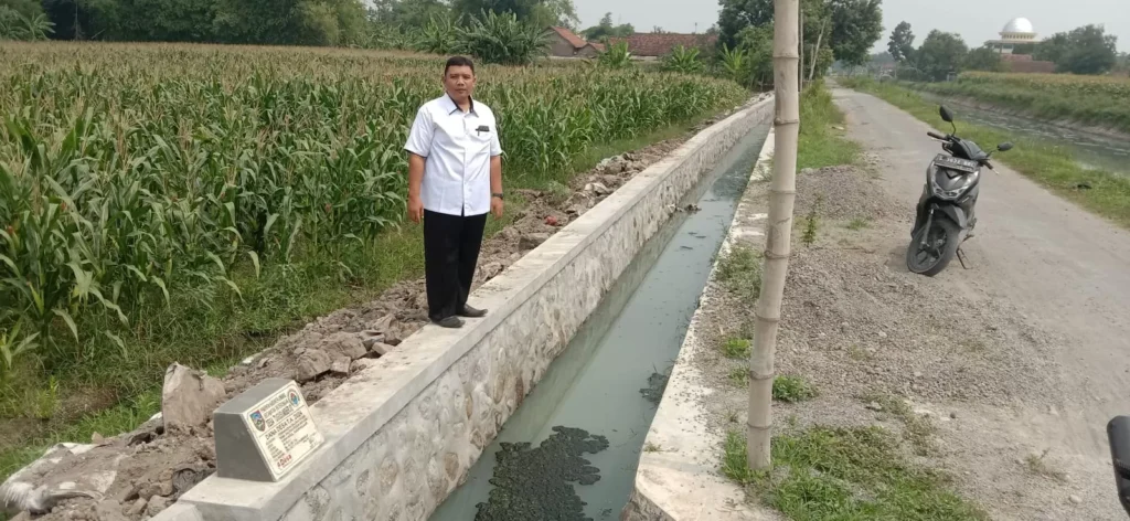 Bayu Hari Satrio Sekdes Tugusumberjo saat menunjukan realisasi pembangunan saluran irigasi di Desa Tugusumberjo. Sumber : Anggi Fridianto/Radar Jombang