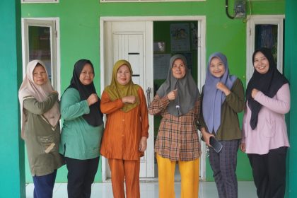 Dewi (paling kanan) bersama rekan-rekannya berpose di depan kantor posyandu. Sumber: dokumentasi kolomdesa.com.
